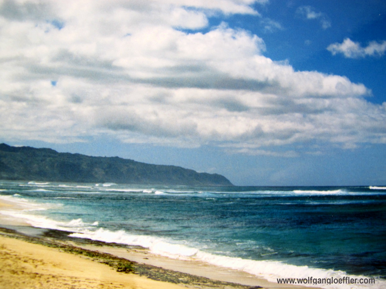 Blick vom Strand über das Blaue Meer auf eine Bergkette in der Ferne