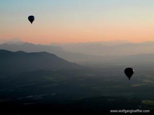 Zwei Ballone fahren in den Sonnenuntergang vor imposanter Bergkulisse