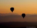 Zwei Heißluftballons im Sonnenuntergang vor Bergkulisse