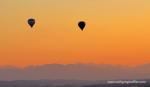 Zwei Heißluftballone schweben im Sonnenuntergang über die Alpen