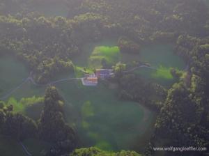 Ein einsamer Bauernhof umgeben von Wiesen und Wald von oben