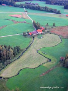 Ein einsaer Bauernhof von oben an einer frisch gemähten Wiese
