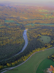 Blick von oben auf einen Fluss, der sich durch einen Wald schlängelt