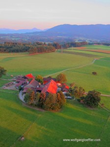 Luftaufnahme eines einsamen Bauernhofs vor Alpenpanorama