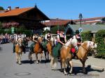 Fünf Frauen im Dirndl reiten auf gestriegelten Pferden
