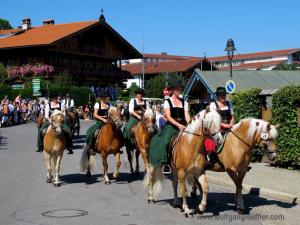 Fünf Frauen im Dirndl reiten auf gestriegelten Pferden