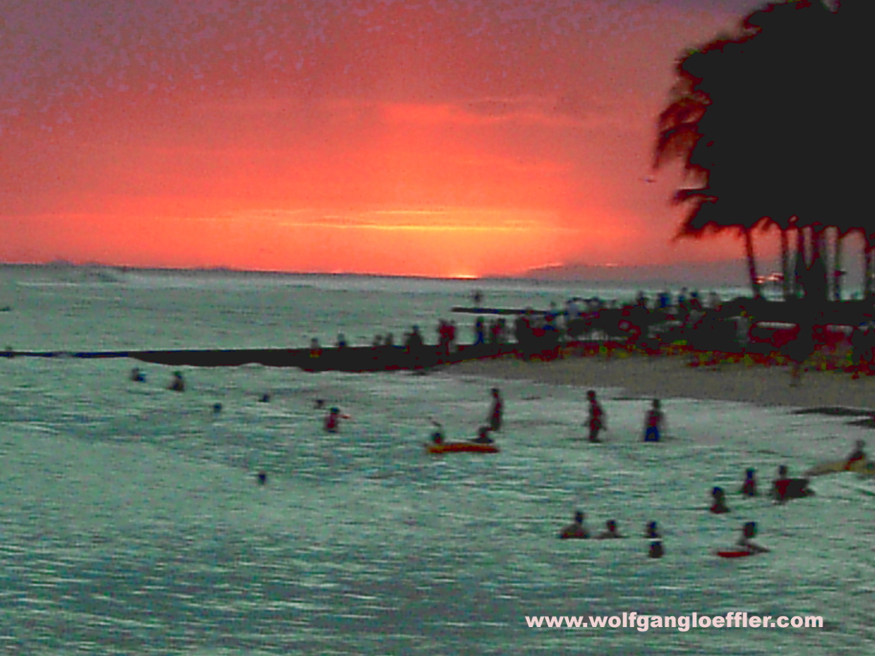Badende Menschen im Meer beim Sonnenuntergang in Waikiki