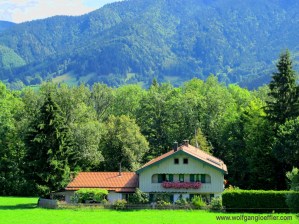 Einsames BAuernhaus am Wald mit Bergen im HIntergrund