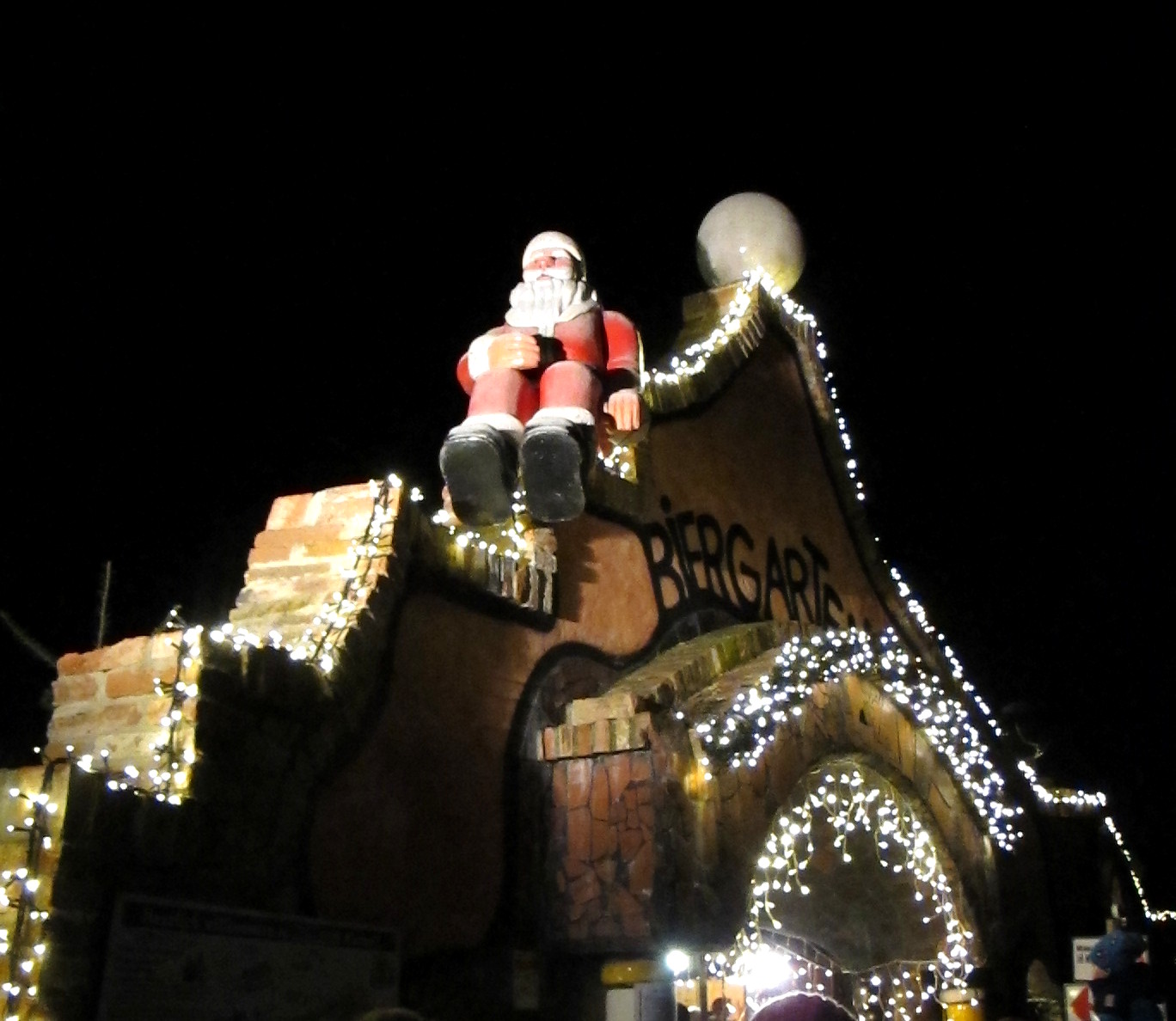 Die Figur des Weihnachtsmann sitzt auf dem Eingang zum Weihnachtsmarkt